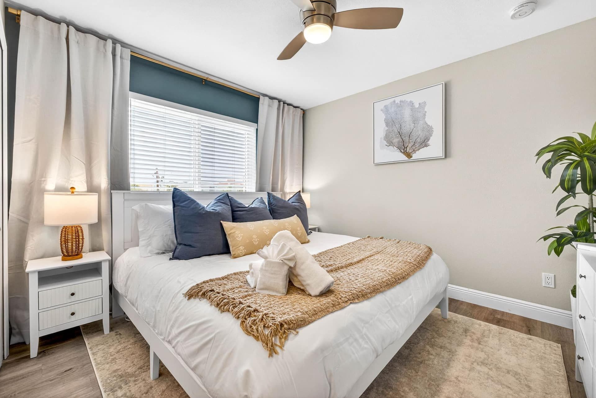 Bedroom with white bedding and coastal art at Coastal Breeze in Indian Rocks Beach, Florida