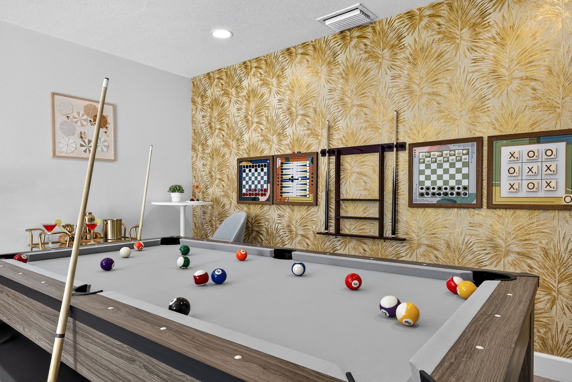 Game room with a pool table and gold palm wallpaper at Luxury Tropical Oasis in Largo, Florida