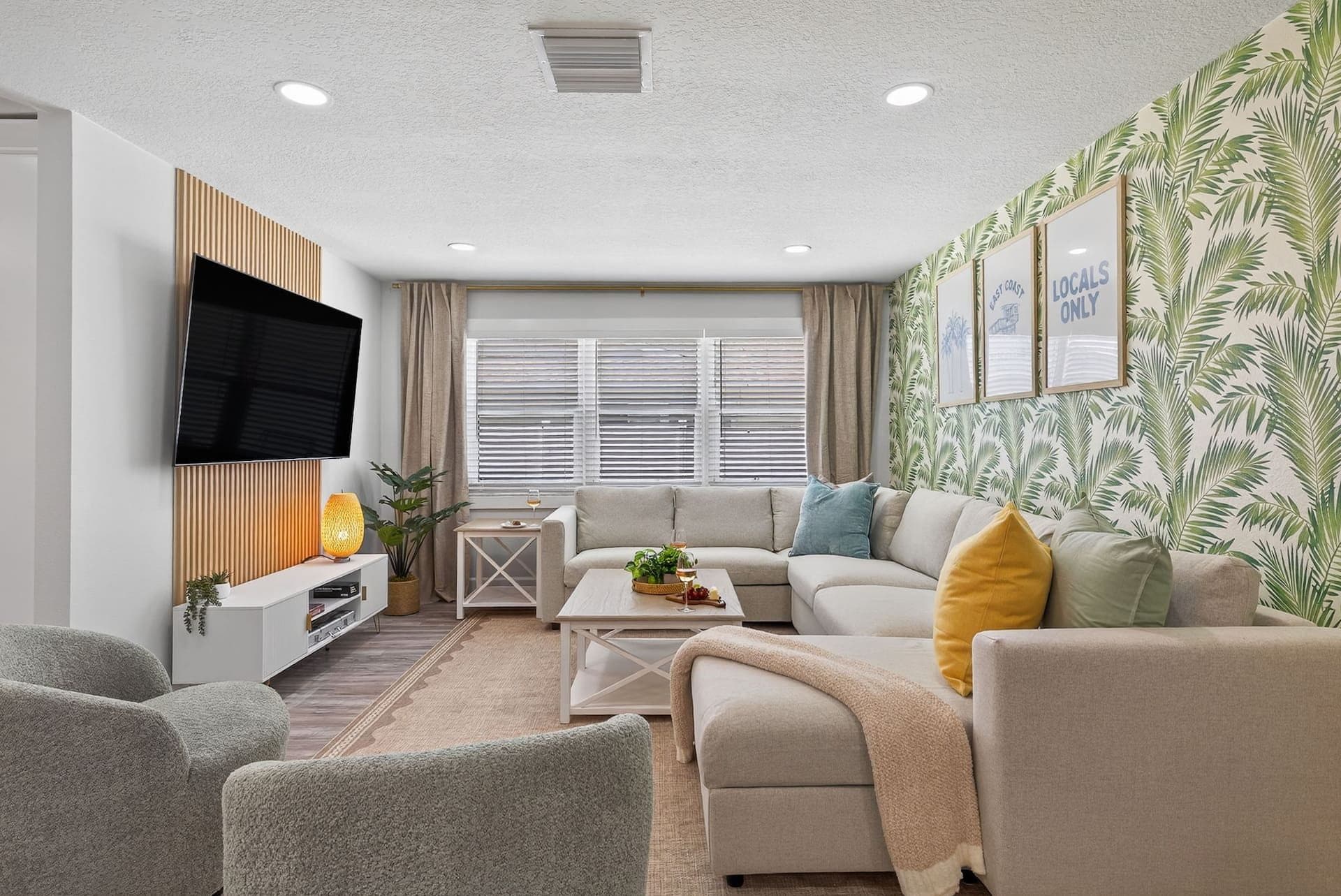 Living room with palm wallpaper and a sectional sofa at Luxury Tropical Oasis in Largo, Florida