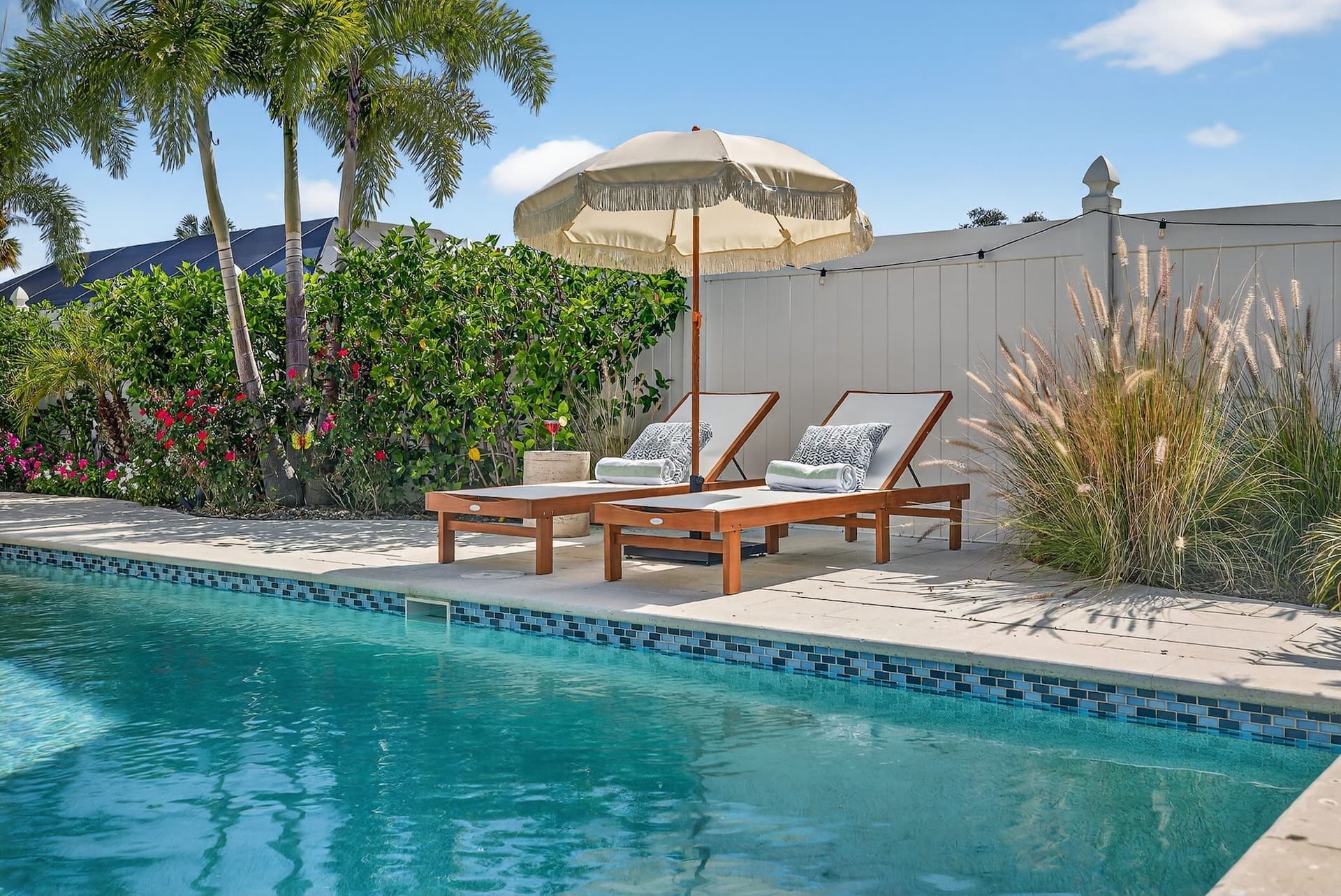 Pool with an umbrella and wood lounge chairs at Luxury Tropical Oasis in Largo, Florida